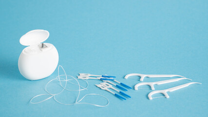 Home dental care kit. Different tools for dental care on blue background. Floss picks floss interdental brush. Top view