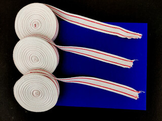 Top view of three White red cotton ribbon rolls. Used for clothing,packing,wrapping. Isolated on blue and black background
