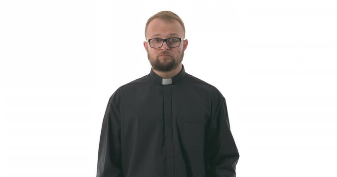 Portrait of young Caucasian priest closed mouth with imaginary zipper and throwing the key. Gesture of silence and swearing not to tell. Isolated on white background