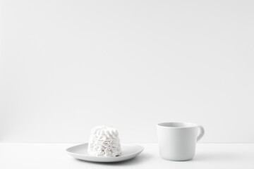 Mug and meringue cake on a white background. Eco-friendly and natural materials in decor and interior design, dessert. Copy space, mock up