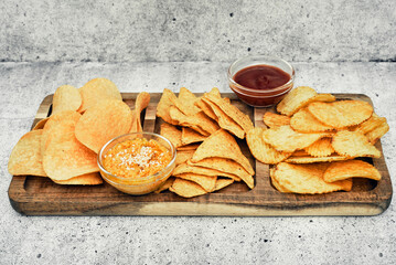 Chips, snacks and crackers on a wooden board. Fast food.