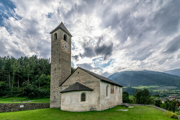 Fototapeta na wymiar The ancient Church of San Giovanni in Prato allo Stelvio, South Tyrol, Italy, under a dramatic sky