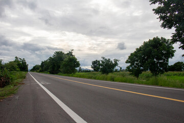 A country road with a gray sky in a corn field