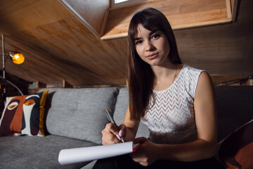 Naklejka premium Writing. Young woman working in videoconference with co-workers at office. Online business, education during coronavirus and quarantine. Work, finance, modern tech concept. View from the screen.