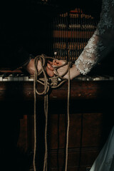 the hands of a guy and a girl are tied with a rope on the piano. a guy and a girl hold a flower with their hands tied