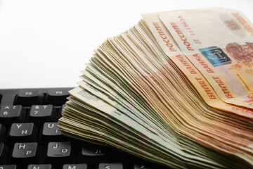 A stack of Russian rubles of different denominations lies on the laptop keyboard.