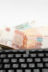 A stack of Russian rubles of different denominations lies on the laptop keyboard.
