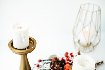 gold candlesticks and candles on a white background. christmas branch with berries . serving the festive table