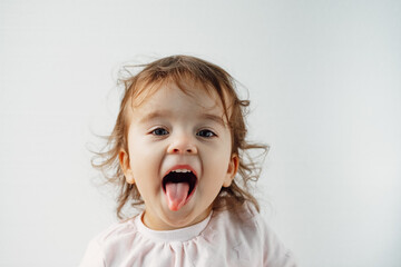 a child on a white background shows his tongue in his mouth, emotions.