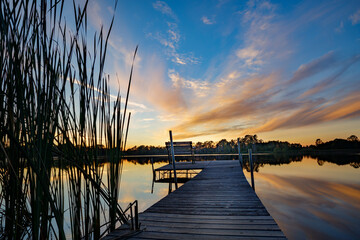 Beautiful sunset reflecting on the water at the public boat landing and dock with bench on Little...