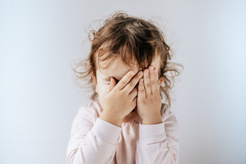 a child on a white background covered his eyes with his hands, afraid, emotions.
