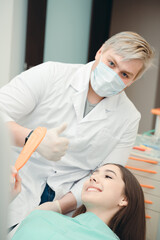 Girl in a chair looking at her teeth with dantes after the procedure