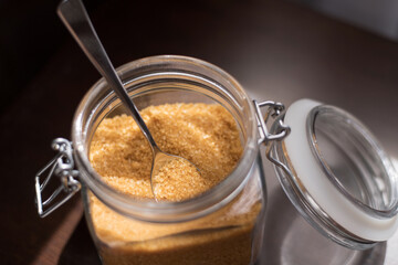 Transparent glass jar with brown sugar cane on a black background
