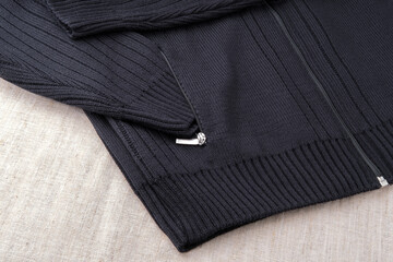 The sleeve of a black men's sweater is tucked into a pocket. Warm clothes, knitted and sewn,...