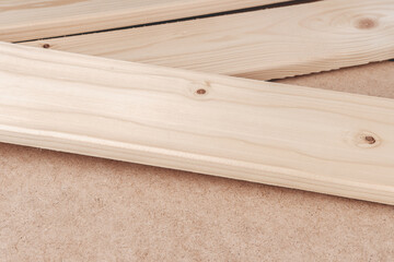 Wooden boards are scattered chaotically on the table. Items for the manufacture of furniture shelves by hand. The slats cast a small shadow on the table covered with paper hardboard.