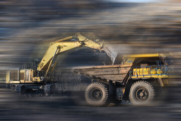 Big dump truck and excavator in coal mine at sunrise 