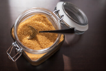 Transparent glass jar with brown sugar cane on a black background