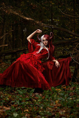Fototapeta premium Stylish and fashionable model girl in the image of Maleficent posing among mystic forest - fairytale story, cosplay. Halloween