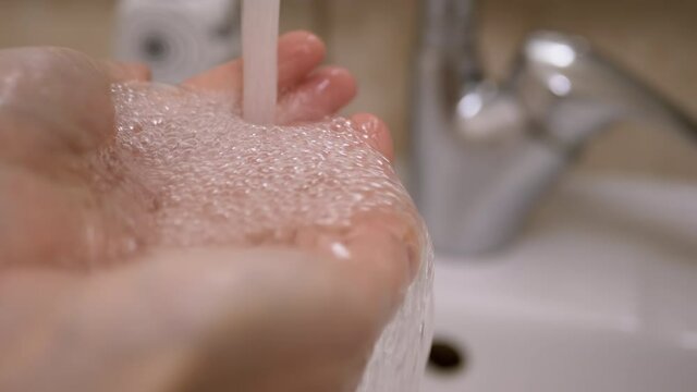 Stream of Fresh Pure Drinking Water is Poured into Female Hands.