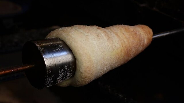 Close up chimney cake baking and rolling