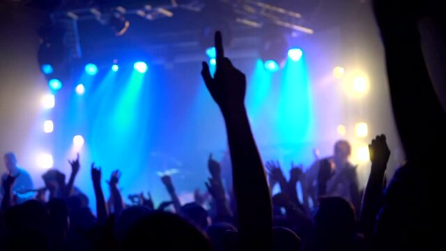 Crowd people at music concert . Cheering crowd takes pictures on a smartphone in front of bright colorful stage lights. Silhouettes of concert crowd in front stage lights of bright . crowd of people