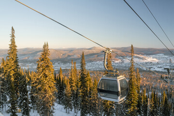 The descent of the closed cabin of the cable car against the background of mountains and trees in...