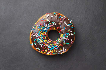 Chocolate donut on black slate background.