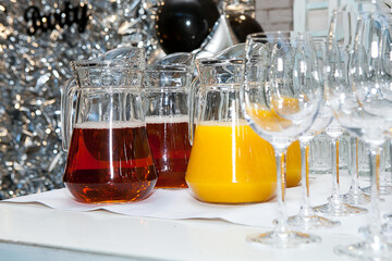 Glasses and glass decanters with orange and grape juice on the table.