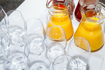 Glasses and glass decanters with orange and grape juice on the table.