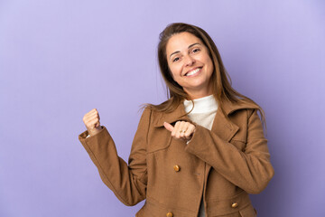 Middle age Brazilian woman isolated on purple background pointing to the side to present a product