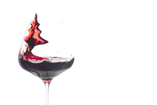 Christmas tree in a red wine splash. Balloon glass.  White background. copy space.