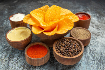 Close up view of homemade potato chips decorated like flower shaped different spices mayonnaise and ketchup on gray background