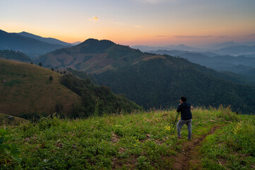 Fototapeta premium Rear view of photographer photographing misty mountain in morning