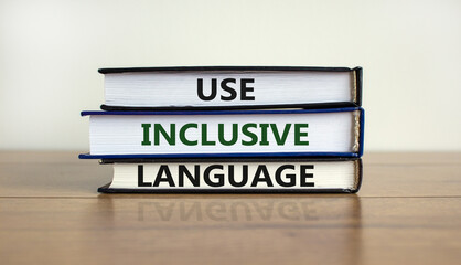 Use inclusive language symbol. Books with words 'Use inclusive language' on beautiful wooden table,...