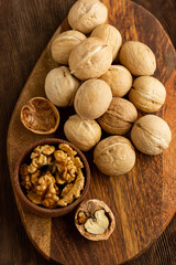 beautiful whole walnuts and a few chopped nuts and walnut kernels in a wooden cup on a wooden table top view
