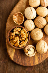 beautiful whole walnuts and a few chopped nuts and walnut kernels in a wooden cup on a wooden table top view