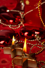 Christmas burning candles with decorations and  presents  at red background. Christmas holiday concept