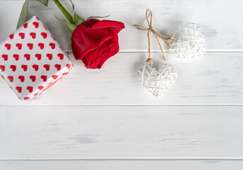 Valentines day gift card with gift box, red rose and two hearts on white wooden background, copy space