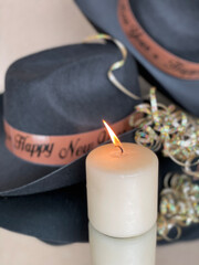 New Years cowboy hats with burning candle on mirrored surface 
