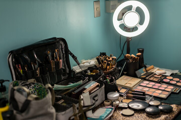LED Light in makeup room.  Decorative cosmetics and tools on dressing table in makeup room. Artist makeup details are laid out on the brow while applying makeup to the girl.