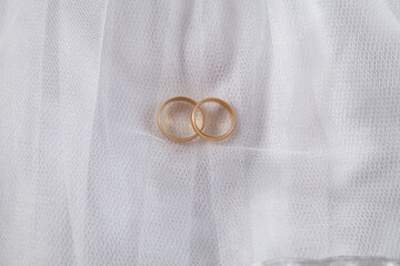 Two wedding rings on an isolated bride's dress.