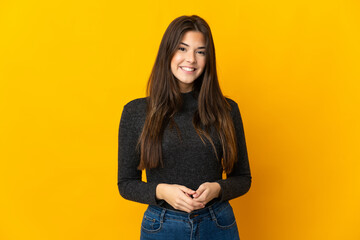 Teenager Brazilian girl isolated on yellow background laughing