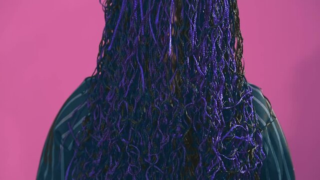 woman with blue afro braids covering her face opens her face with her hands