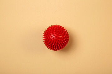 Rubber massager. Red bumpy rubber sphere on yellow background.