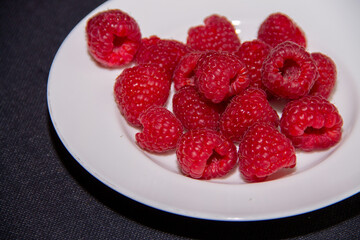 ripe red raspberries on a white plate