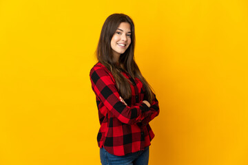 Teenager Brazilian girl isolated on yellow background with arms crossed and looking forward