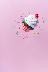 Colorful cupcake with colorful sugar decoration on pastel pink  background.