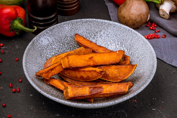 Potatoes and sweet potato fries on black concrete table
