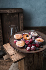 Still life with frozen berries and fruits in a brown plate on a vintage background. Side view. Culinary cooking backgrounds.