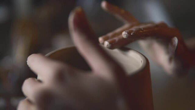 Concept of handcraft therapy, ceramics and creativity. Macro or close up shot of female hands sculpting a clay pot on pottery wheel. Woman creating a pice of kitchenware.